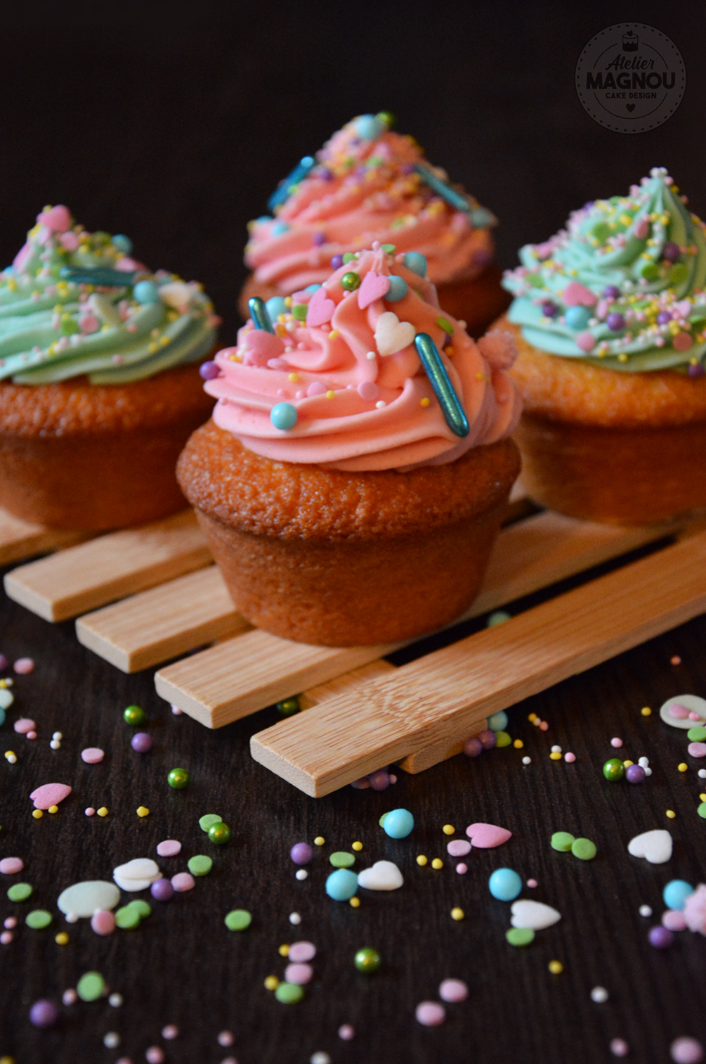 Ponquecitos o cupcakes de vainilla con crema de mantequilla y chocolate blanco, de color rosado y azul, adornados con sprinkles de colores